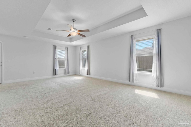 carpeted spare room with ceiling fan and a raised ceiling