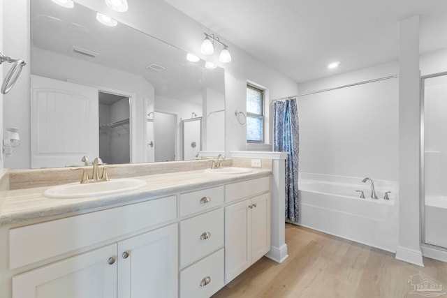 bathroom featuring dual bowl vanity, separate shower and tub, and hardwood / wood-style flooring