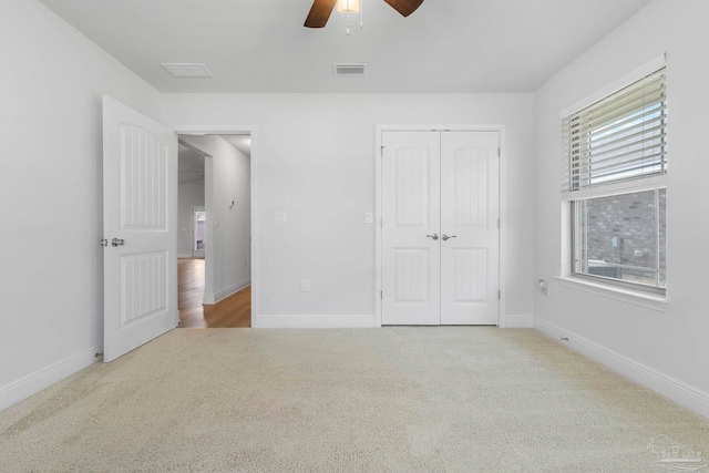 unfurnished bedroom featuring ceiling fan, light colored carpet, a closet, and multiple windows