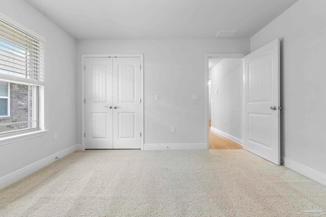 unfurnished bedroom featuring a closet, light colored carpet, and multiple windows