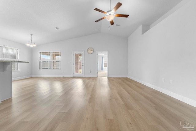 unfurnished living room featuring ceiling fan with notable chandelier, vaulted ceiling, and light hardwood / wood-style floors