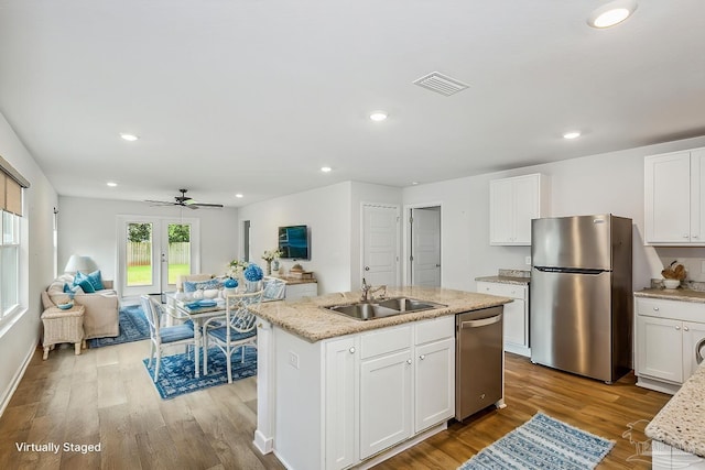 kitchen with white cabinetry, stainless steel appliances, sink, and a center island with sink