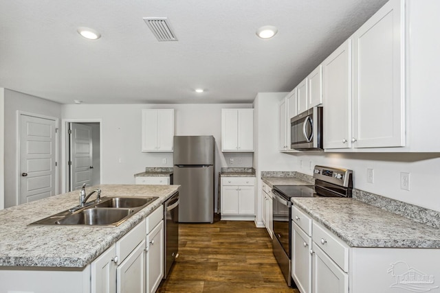 kitchen with a kitchen island with sink, dark wood-type flooring, stainless steel appliances, sink, and white cabinets