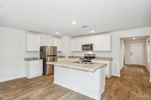 kitchen with sink, white cabinetry, a center island with sink, hardwood / wood-style flooring, and stainless steel appliances