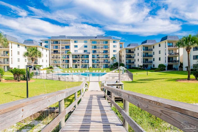 exterior space with a balcony, a community pool, and a yard