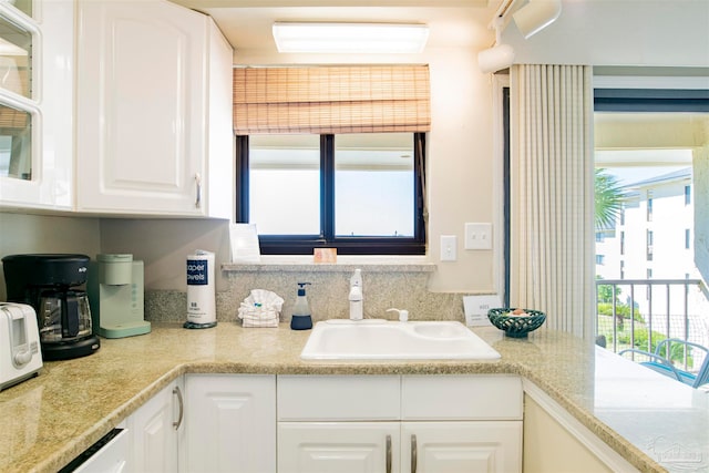 kitchen featuring sink, white cabinetry, and light stone counters