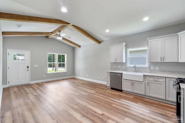 kitchen featuring a sink, appliances with stainless steel finishes, vaulted ceiling with beams, and light countertops