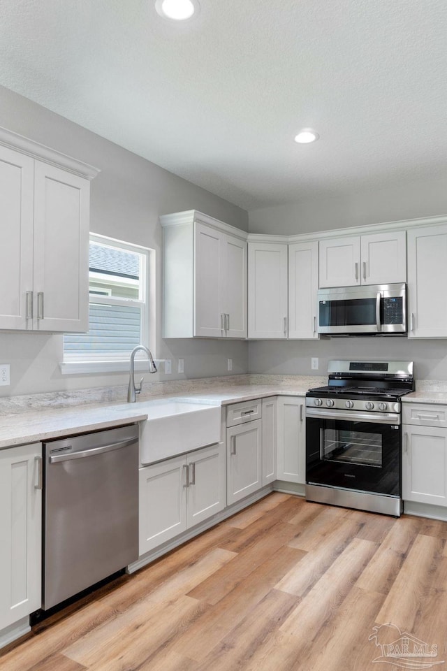 kitchen featuring recessed lighting, appliances with stainless steel finishes, white cabinetry, and light wood-type flooring