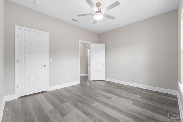 unfurnished bedroom with a ceiling fan, wood finished floors, visible vents, and baseboards