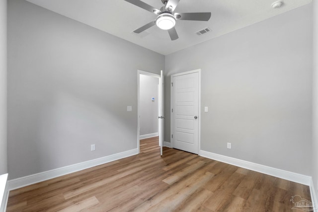 empty room with visible vents, light wood-style flooring, a ceiling fan, and baseboards