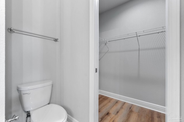 bathroom with baseboards, toilet, and wood finished floors