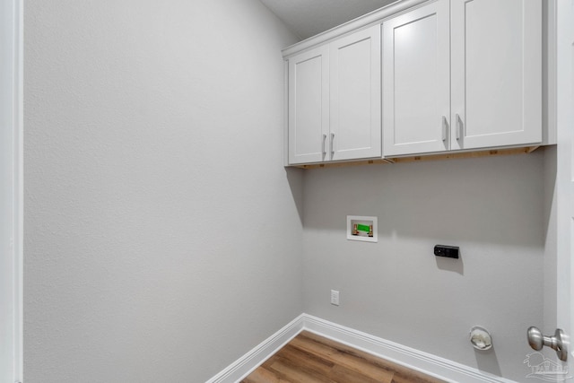 washroom featuring cabinet space, wood finished floors, baseboards, and washer hookup