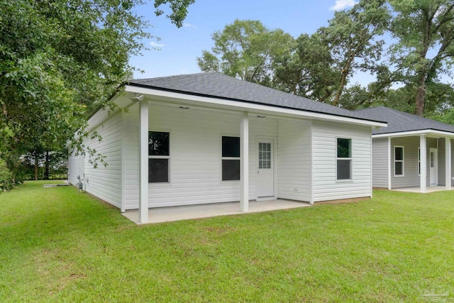 back of property with a patio area, a lawn, and roof with shingles