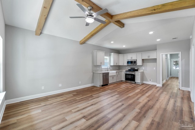 kitchen featuring a sink, appliances with stainless steel finishes, light wood finished floors, baseboards, and light countertops