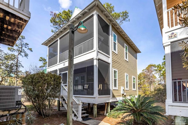 rear view of house with cooling unit and a sunroom