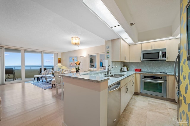13753 Perdido Key Dr Unit 504, Perdido Key, FL 32507 - kitchen featuring stainless steel appliances, a sink, a peninsula, light stone counters, and backsplash