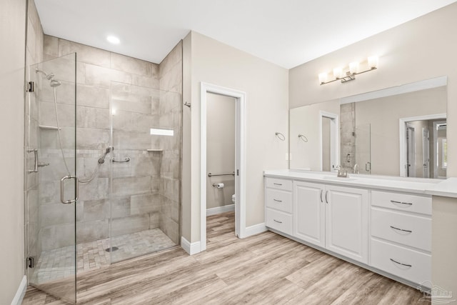 full bathroom featuring baseboards, a shower stall, toilet, vanity, and wood finished floors