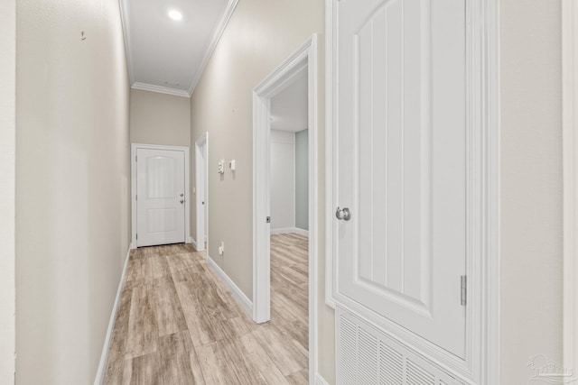 corridor featuring baseboards, light wood finished floors, and ornamental molding