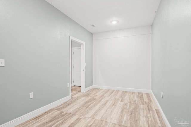 spare room featuring light wood finished floors, baseboards, and visible vents