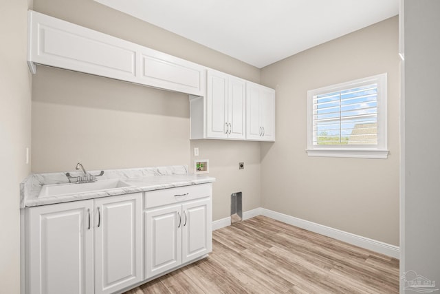 clothes washing area with cabinet space, electric dryer hookup, baseboards, a sink, and light wood finished floors