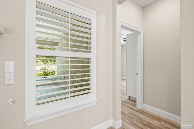 hallway featuring light wood-style flooring and baseboards