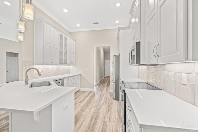 kitchen featuring light countertops, a sink, white cabinetry, glass insert cabinets, and pendant lighting