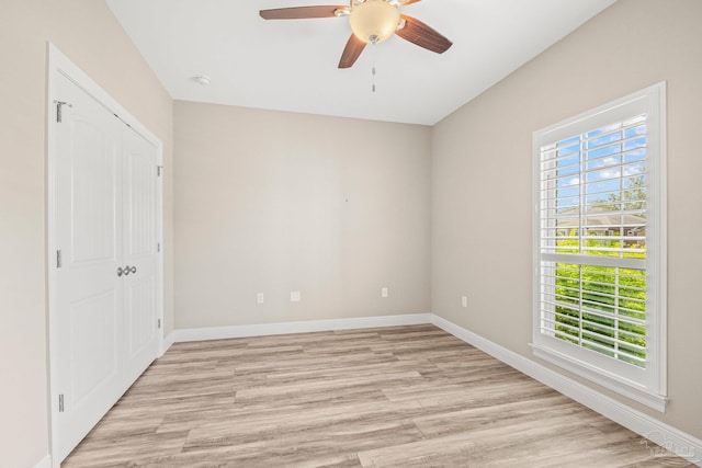 unfurnished bedroom featuring baseboards, ceiling fan, light wood finished floors, and a closet