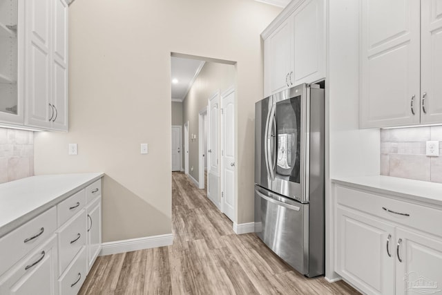 kitchen featuring white cabinetry, refrigerator with glass door, tasteful backsplash, light countertops, and light wood-style floors