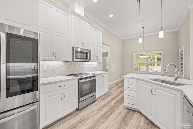 kitchen featuring white cabinets, stainless steel appliances, light wood-type flooring, decorative light fixtures, and sink