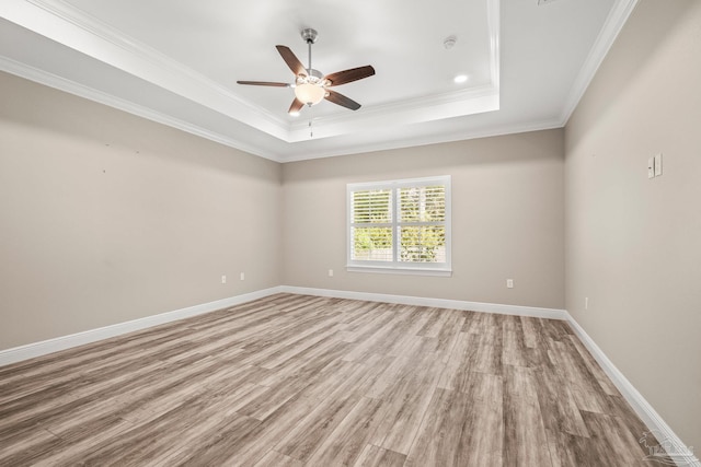 unfurnished room featuring a ceiling fan, baseboards, ornamental molding, a raised ceiling, and light wood-style floors