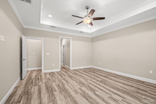 unfurnished bedroom with ornamental molding, light wood finished floors, baseboards, a ceiling fan, and a tray ceiling