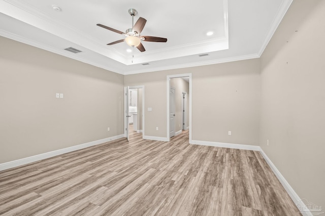 unfurnished room featuring ceiling fan, ornamental molding, a tray ceiling, and light hardwood / wood-style floors