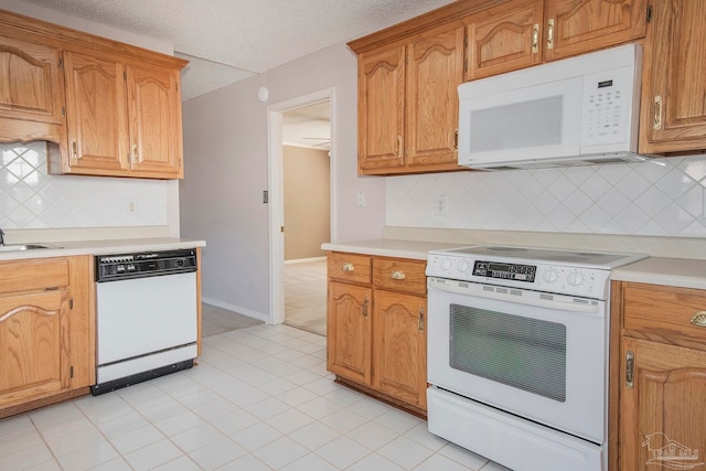 kitchen with light tile patterned floors, backsplash, and white appliances