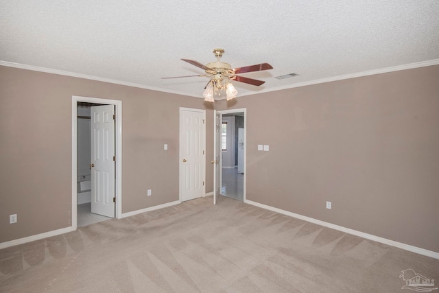 unfurnished bedroom featuring ensuite bathroom, a textured ceiling, ceiling fan, light carpet, and ornamental molding