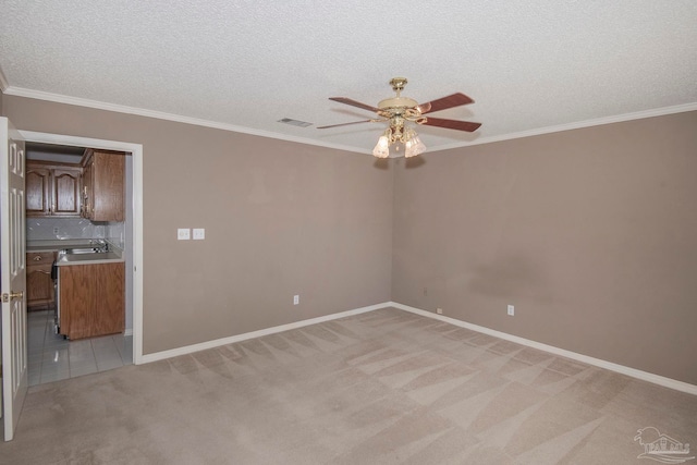 carpeted empty room featuring ornamental molding, a textured ceiling, sink, and ceiling fan