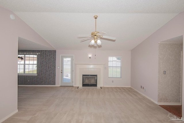 unfurnished living room with lofted ceiling, ceiling fan, a textured ceiling, and plenty of natural light