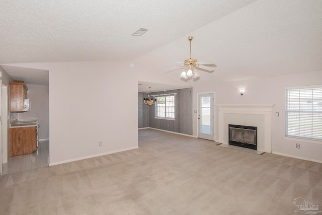 unfurnished living room with light carpet, a textured ceiling, ceiling fan with notable chandelier, and vaulted ceiling