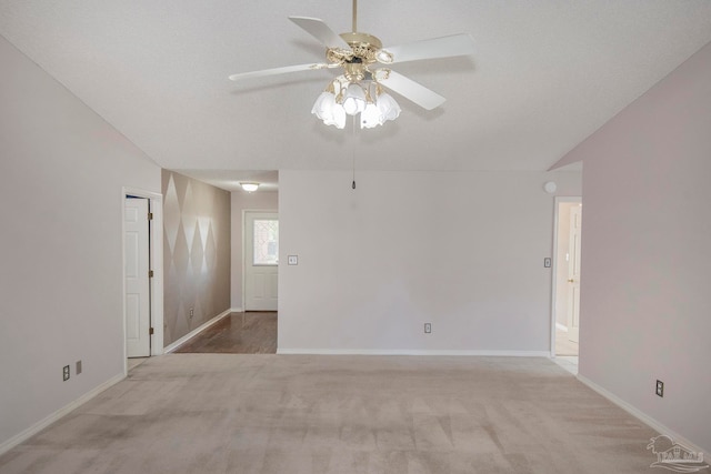 carpeted spare room featuring lofted ceiling, a textured ceiling, and ceiling fan