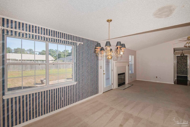 unfurnished dining area with a textured ceiling, carpet floors, a tiled fireplace, vaulted ceiling, and a notable chandelier