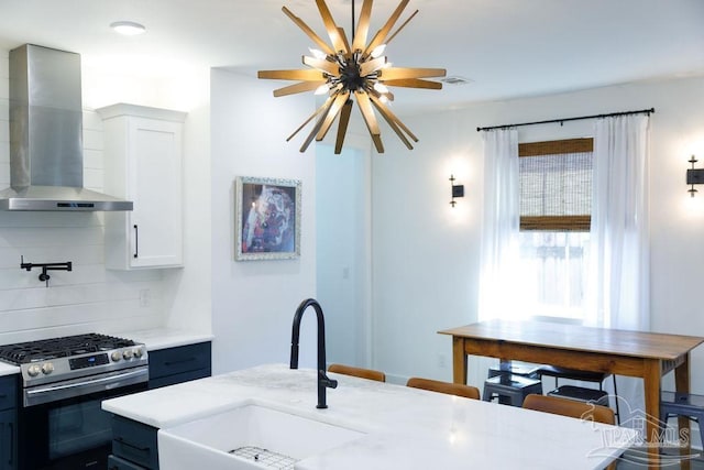 kitchen with visible vents, stainless steel range with gas stovetop, a sink, wall chimney exhaust hood, and tasteful backsplash