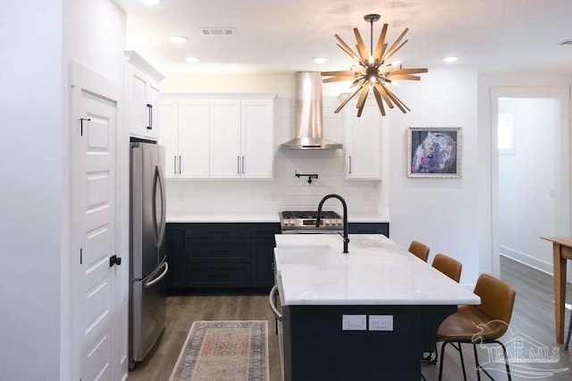 kitchen featuring visible vents, a breakfast bar, exhaust hood, dark wood-style floors, and stainless steel appliances