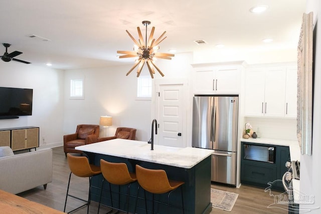 kitchen featuring visible vents, freestanding refrigerator, white cabinets, light wood-style floors, and open floor plan