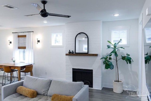 living room with visible vents, a ceiling fan, dark wood finished floors, a fireplace, and baseboards