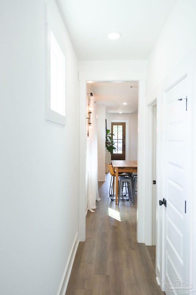 hallway featuring dark wood finished floors and baseboards