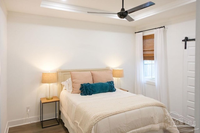 bedroom featuring a barn door, baseboards, dark wood-type flooring, and ceiling fan