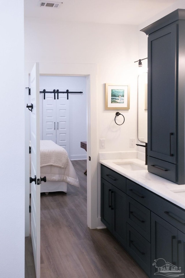 full bath with visible vents, ensuite bathroom, a sink, wood finished floors, and double vanity