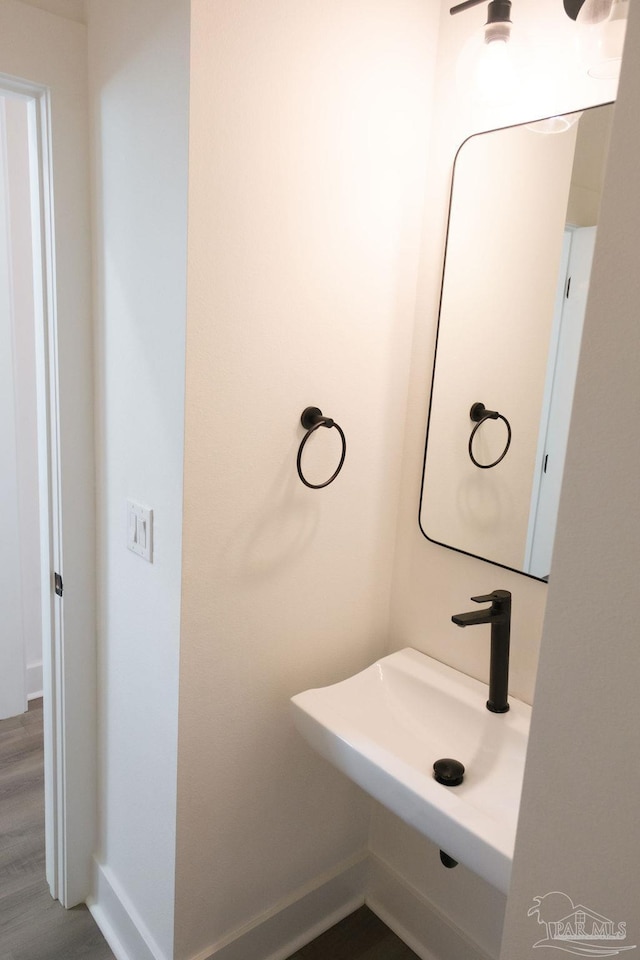 bathroom with wood finished floors, baseboards, and a sink