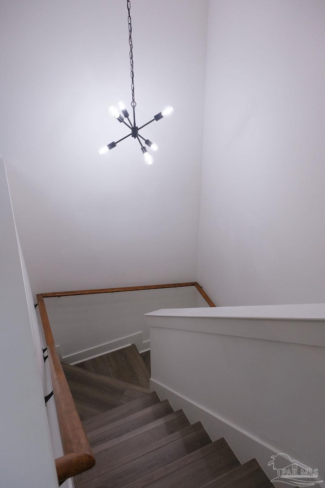 stairs featuring an inviting chandelier and wood finished floors