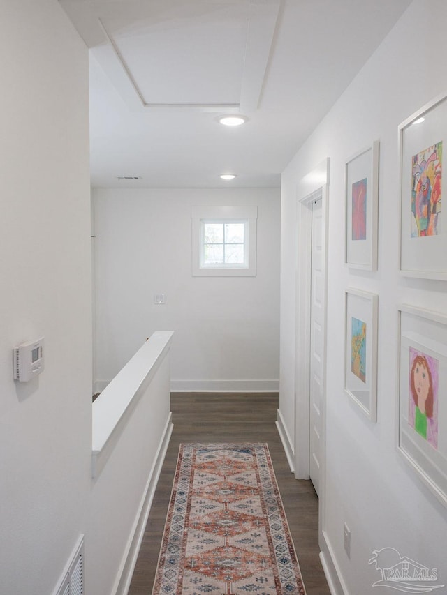 hall featuring visible vents, baseboards, and dark wood-style flooring