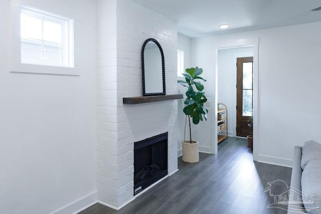 living area with baseboards, a fireplace, and dark wood-style flooring